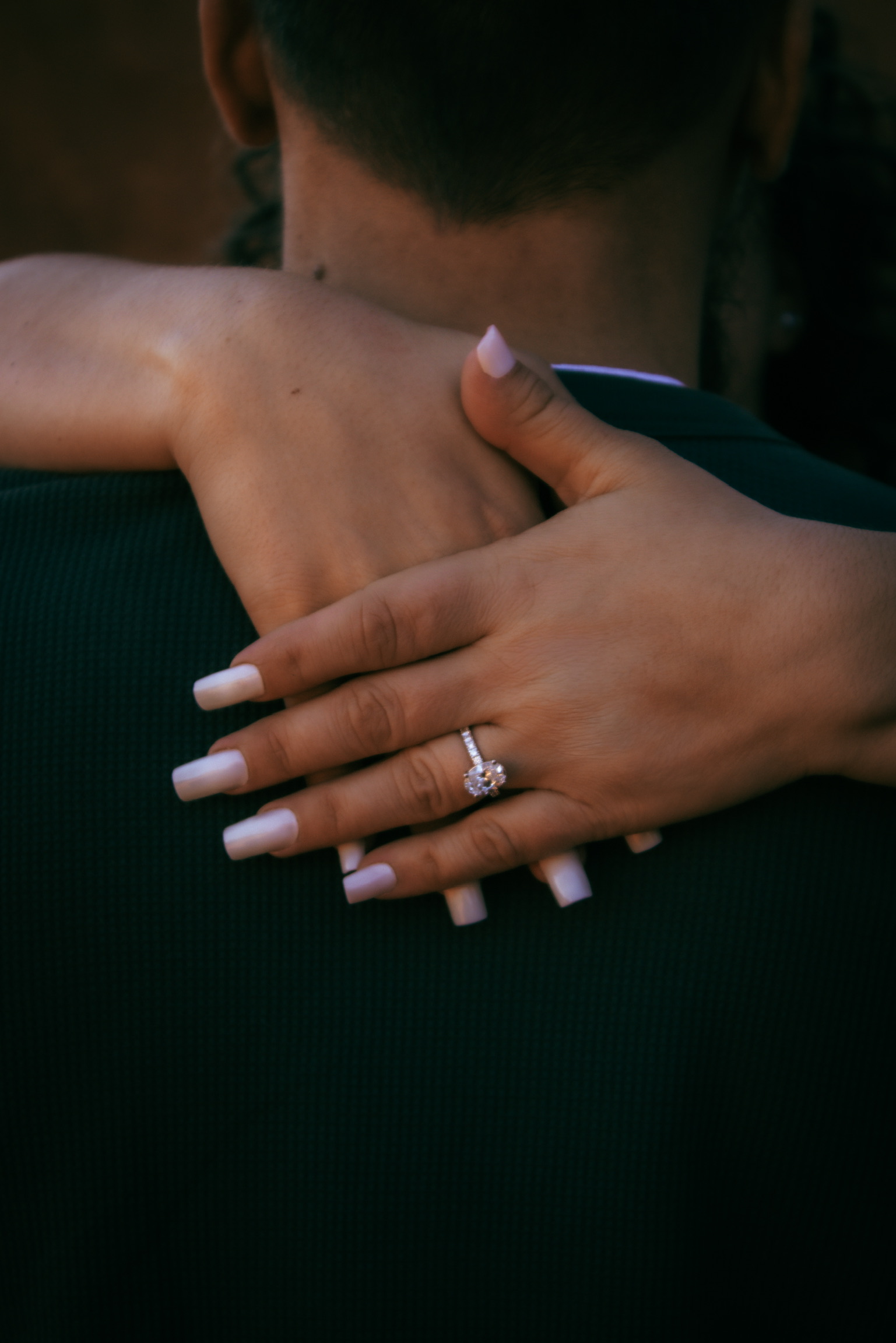 Emirjeta's hand with engagement ring resting on Adam's shoulder